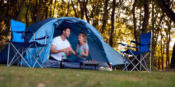 テントの中でカップルバーベキューグリルとシャンパンを飲むことによって座ってキャンプ — ストック写真