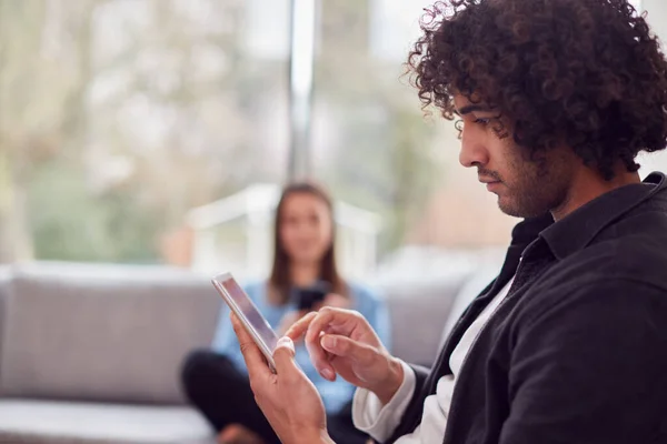 Pareja Joven Relajada Casa Sentada Sofá Usando Tableta Digital Teléfono — Foto de Stock