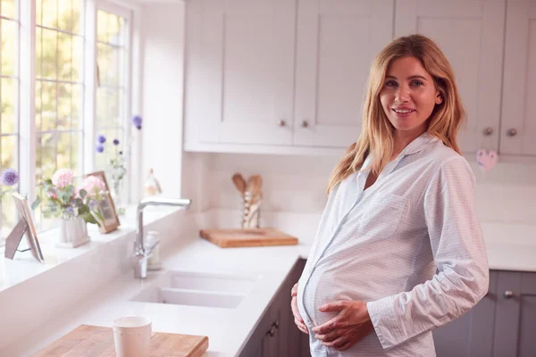 穿着睡衣站在厨房里拿着木桶的孕妇的画像 — 图库照片