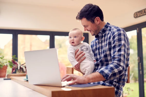 Evde Dizüstü Bilgisayar Kullanırken Dizlerinin Üzerinde Gülümseyen Oğlunu Kucağında Tutmak — Stok fotoğraf