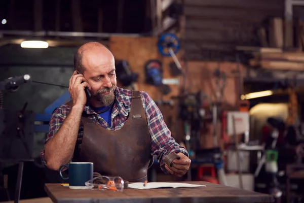 Mature Male Blacksmith Working Design Forge Whilst Using Mobile Phone — Stock Photo, Image