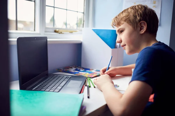 在健康大流行期间 男孩坐在课桌前 用笔记本电脑上网学习 — 图库照片