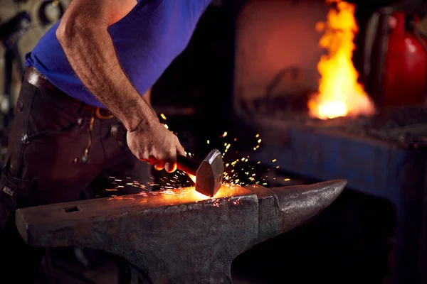 火花とろう付けフォージを背景に アンビル上の男性鍛冶屋の金属細工の閉鎖 — ストック写真