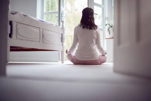 ヨガポーズで瞑想する寝室の床に座っているパジャマ姿のアジア系熟女の後ろ姿 — ストック写真