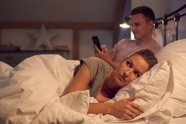 Homem Casa Usando Telefone Celular Cama Enquanto Mulher Acordada Parece — Fotografia de Stock