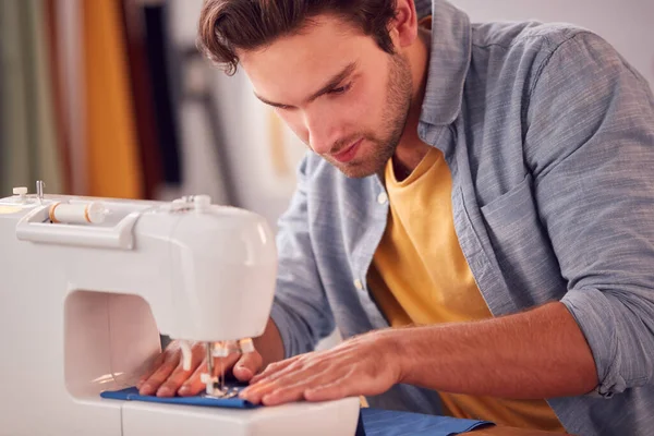 在工作室里用缝纫机在时装行业工作的男生或企业主的近照 — 图库照片
