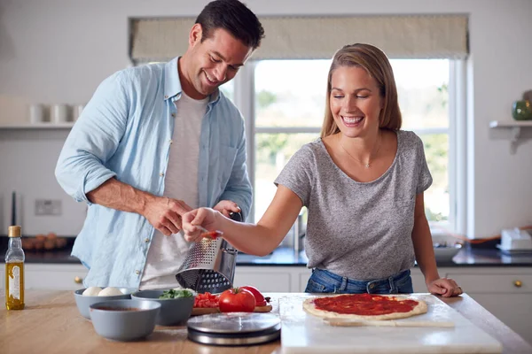 キッチン家庭で夫婦でベースにトマトソースを広げる女が一緒に自家製ピザを準備 — ストック写真