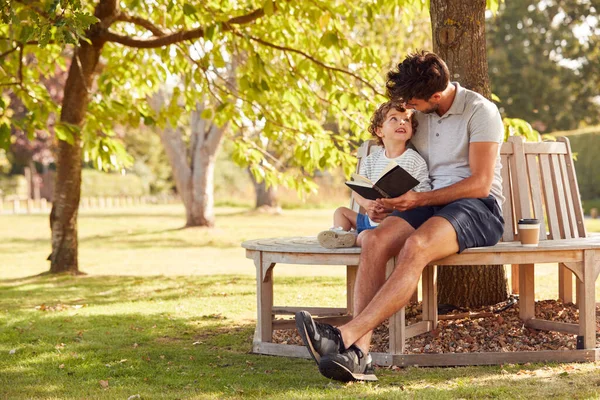 Vater Sitzt Mit Sohn Auf Parkbank Unter Baum Und Liest — Stockfoto