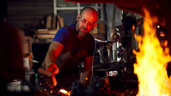 鍛冶場で金属加工加熱にワイヤーブラシを使用して男性鍛冶屋 — ストック写真