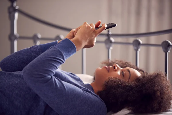 Γυναίκα Ξαπλωμένη Στο Κρεβάτι Κινητό Τηλέφωνο Φορώντας Πιτζάμες — Φωτογραφία Αρχείου