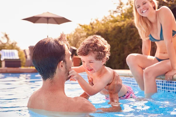 屋外スイミングプールで夏休みを楽しんでいる若い息子と家族 — ストック写真