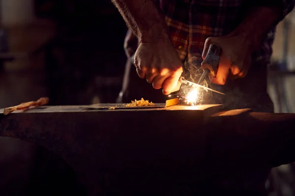ライトフォージにアンビル上の薪と男性鍛冶屋照明木片のクローズアップ — ストック写真