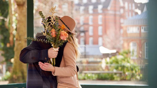 낭만적 남자가 자신이 꽃들의 꽃다발 얼굴을 감추고 여자를 — 스톡 사진