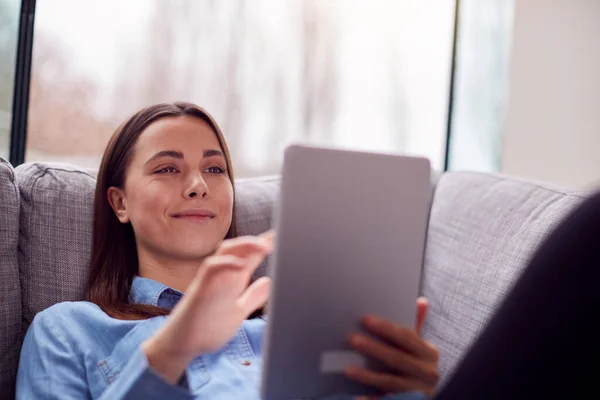 Sorrindo Jovem Mulher Casa Deitada Sofá Olhando Para Tablet Digital — Fotografia de Stock