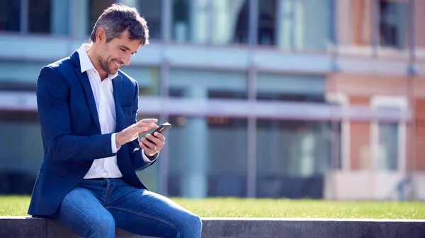 携帯電話を使用してオフィスの外に座って休憩中のビジネスマン — ストック写真