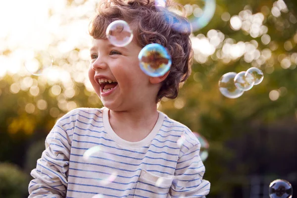 在花园追逐中快乐的小男孩和爆裂的气泡 — 图库照片