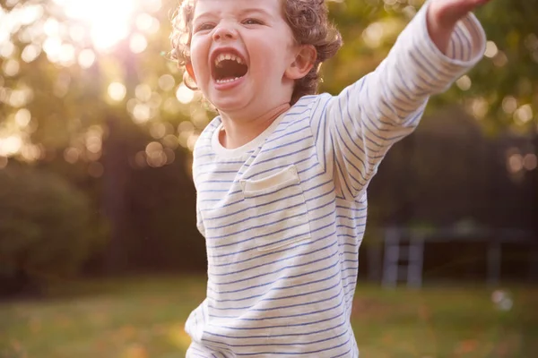 在花园追逐中快乐的小男孩和爆裂的气泡 — 图库照片