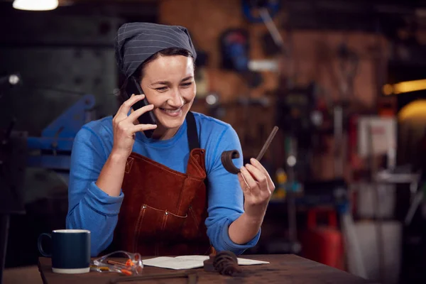 Kvinnlig Smed Arbetar Design Smedja Medan Använder Mobiltelefon — Stockfoto