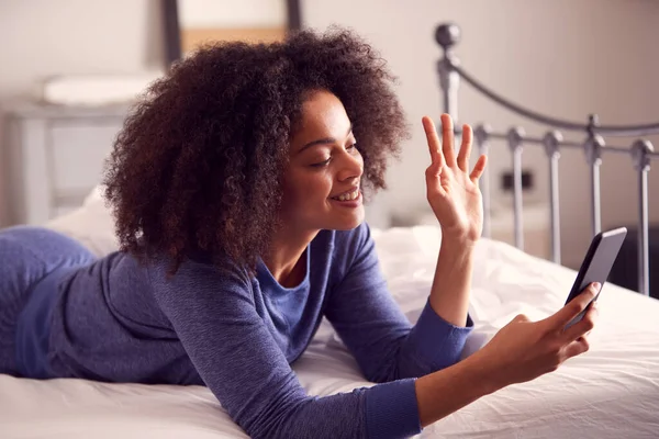 Cep Telefonlu Pijamalı Yatakta Uzanmış Görüntülü Sohbet Eden Bir Kadın — Stok fotoğraf