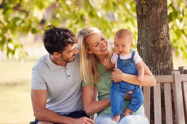 夏の公園の木の下で一緒に座っている赤ちゃんの娘と家族 — ストック写真