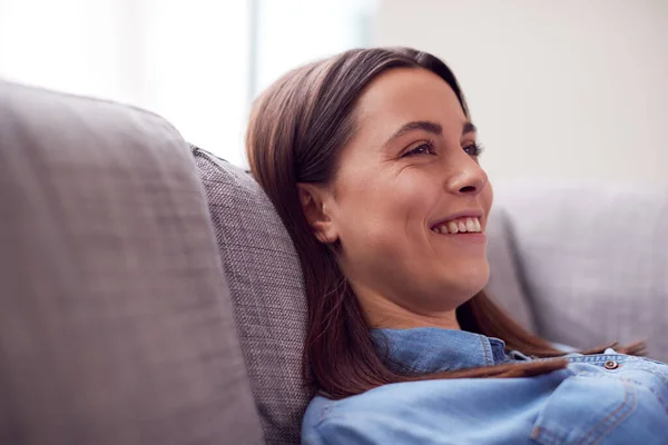 Χαμογελώντας Νεαρή Γυναίκα Στο Σπίτι Ξαπλωμένη Στον Καναπέ Βλέποντας Τηλεόραση — Φωτογραφία Αρχείου