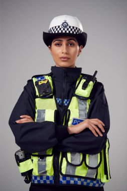 Studio Portrait Of Serious Young Female Police Officer Against Plain Background clipart