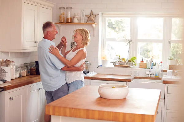引退したロマンチックなカップルは一緒に自宅でキッチンで踊る — ストック写真