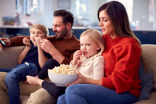 ポップコーンのテレビを見ながらソファに座っている家族 — ストック写真