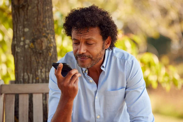 Зрелый Мужчина Сидящий Скамейке Парке Деревом Летом Разговаривает Мобильному Телефону — стоковое фото