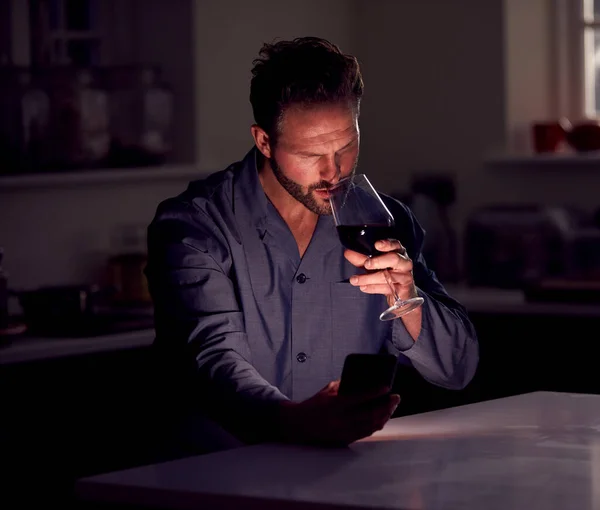 Man Wearing Pyjamas Sitting Kitchen Glass Wine Night Using Mobile — Stockfoto