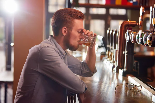 不快乐的男人一个人坐在酒吧里喝着威士忌 — 图库照片