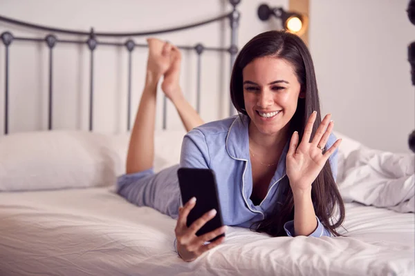 Waving Woman Mobile Phone Wearing Pyjamas Having Video Chat Lying — Stock Photo, Image