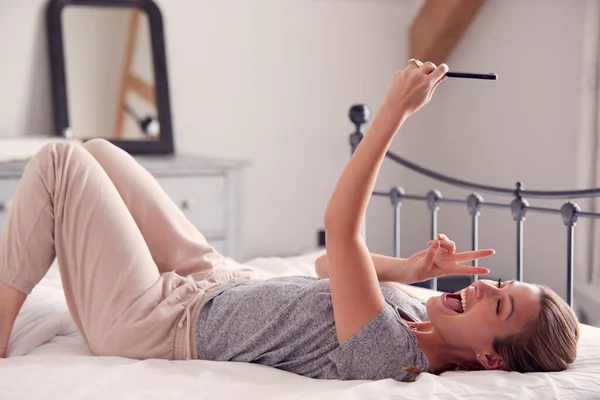 Mujer Usando Pijamas Tomando Selfie Haciendo Paz Teléfono Móvil Acostada — Foto de Stock