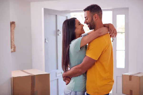 Loving Couple With Keys To New Home Hugging By Front Door On Moving Day