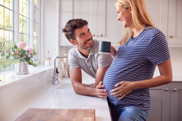 コーヒーを飲みながら妊娠中の女性とチャットする男とキッチンでカップル — ストック写真