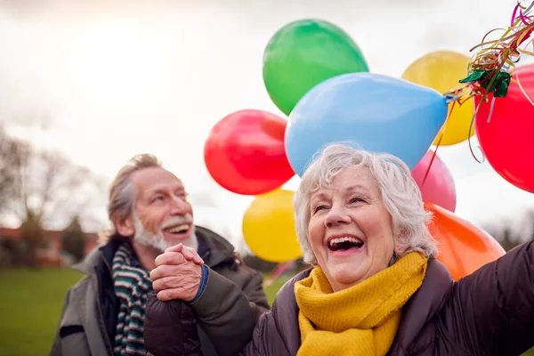 Kochająca Para Starszych Holding Balony Cieszący Się Jesienią Lub Zimą — Zdjęcie stockowe