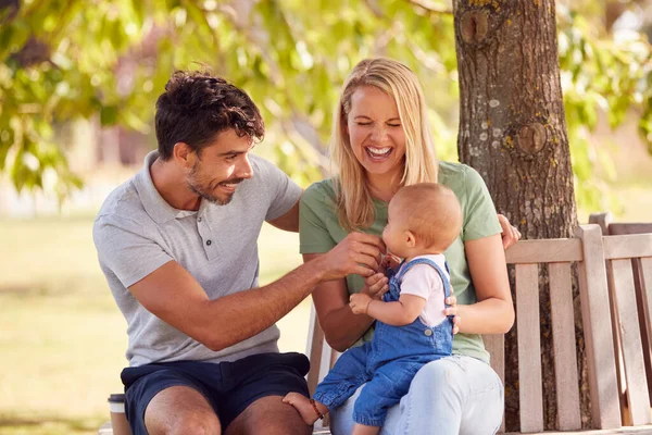 夏の公園の木の下で一緒に座っている赤ちゃんの娘と家族 — ストック写真