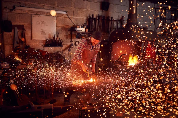 Blazing Forgeを背景にしたAnvilでの男性鍛冶屋の金属加工 — ストック写真