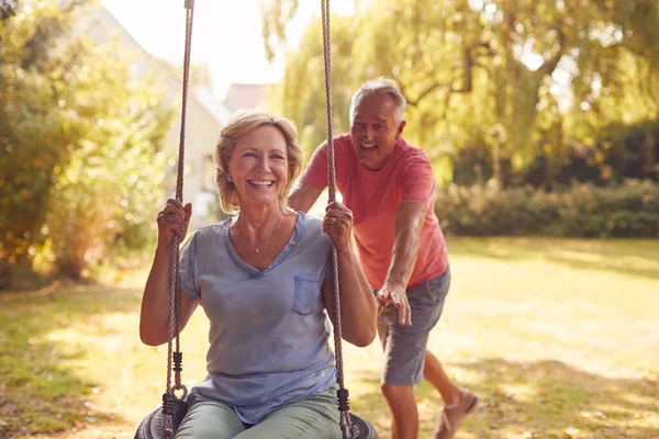 Pensionato Coppia Avendo Divertimento Con Uomo Spingendo Donna Giardino Swing — Foto Stock