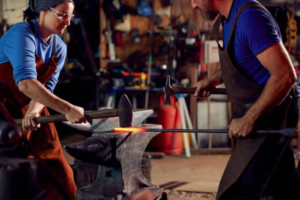 オスとメスの鍛冶屋は火花とアンビルで金属細工をハンマー — ストック写真