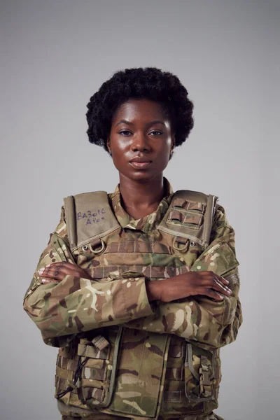 Studio Portrait Of Serious Young Female Soldier In Military Uniform Against Plain Background