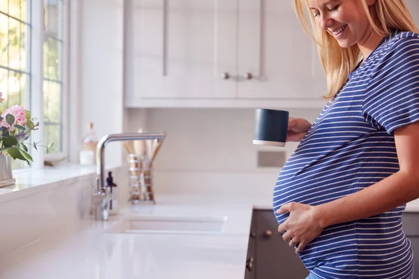 Zbliżenie Kobiety Ciąży Stojącej Przy Oknie Kuchennym Dotykając Żołądka Relaks — Zdjęcie stockowe