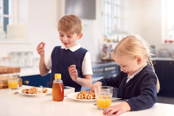 キッチンで制服を着た子供たち朝食ワッフルとシロップを食べる — ストック写真
