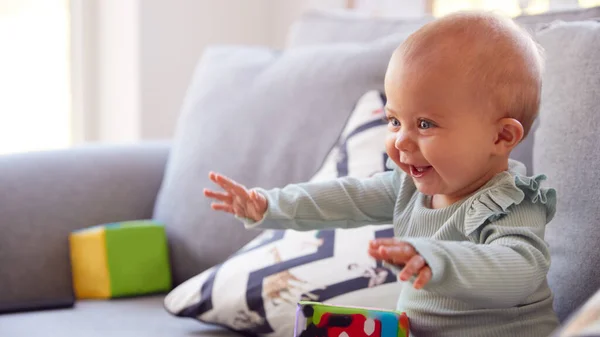 Cute Baby Girl Siedzi Kanapie Bawiąc Się Kształtu Zabawki — Zdjęcie stockowe