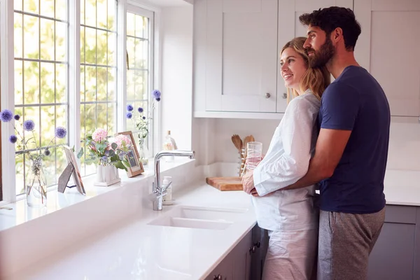 Pareja Con Hombre Abrazando Mujer Embarazada Usando Pijama Pie Cocina —  Fotos de Stock