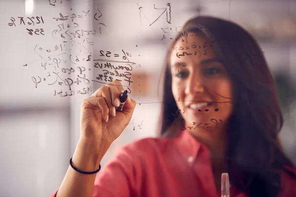 ブレインストーミングビジネスウーマンや数学者がオフィスのガラス画面上でグラフ計算を描く — ストック写真
