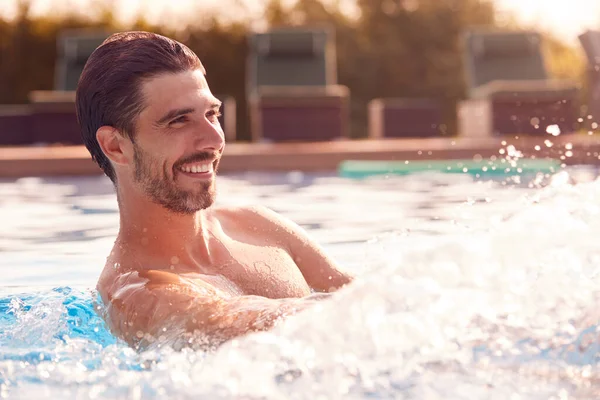 屋外スイミングプールでの夏休みに水をスプラッシング笑顔男 — ストック写真