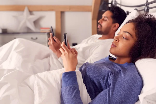 Yatakta Uzanan Iletişim Kuramayan Cep Telefonlarını Kullanmaya Bağımlı Pijamalı Bir — Stok fotoğraf