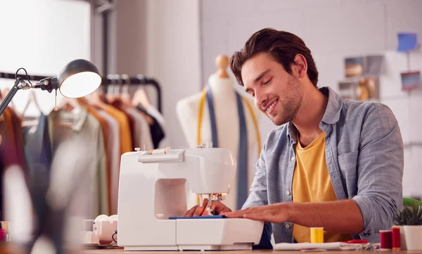 在工作室用缝纫机在时装行业工作的男性学生或企业主的微笑 — 图库照片