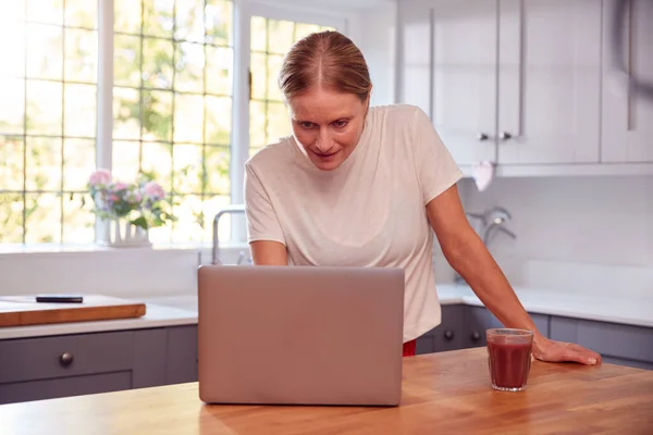 Evde Giyinen Olgun Kadın Mutfakta Giyiniyor Dizüstü Bilgisayarında Etkinlik Var — Stok fotoğraf